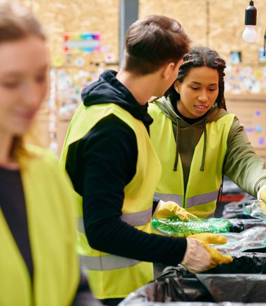 Young volunteers in gloves and safety vests sorting trash together in a community effort.